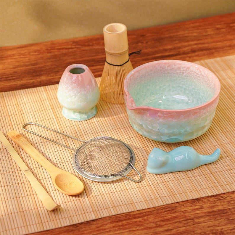 Pu&ograve; includere: Un set da t&egrave; matcha con una ciotola dai colori pastello, un frullatore e accessori in ceramica. Il set include una frusta di bamb&ugrave;, un setaccio, un cucchiaio e un piccolo riposo a forma di gatto. La ciotola ha una superficie strutturata.