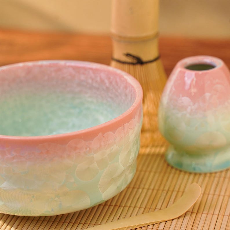 Pu&ograve; includere: Una ciotola di matcha in ceramica, chashaku, chasen e un piccolo contenitore. La ciotola ha una sfumatura di colori, dal rosa al verde. Il chasen &egrave; una frusta di bamb&ugrave; e il chashaku &egrave; un cucchiaio di bamb&ugrave;. Il piccolo contenitore &egrave; anch'esso rosa e verde.