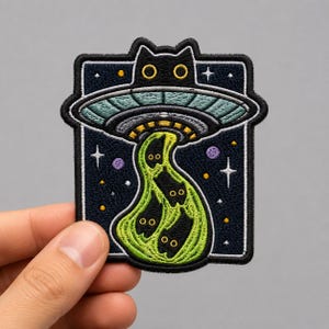 May include: An embroidered patch featuring a black cat head silhouette integrated into a flying saucer. The saucer emits a bright green tractor beam containing three small black cat figures against a dark blue starry night sky background.