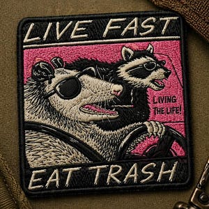 May include: Embroidered patch with the text "LIVE FAST EAT TRASH" and a pink background. The patch features a raccoon and an opossum wearing sunglasses and driving. The phrase "LIVING THE LIFE!" is also included.