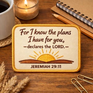 May include: A rectangular patch with a cream background and a gold border. The patch features the text "For I know the plans I have for you, -declares the LORD.- JEREMIAH 29:11" in brown script. A yellow sun graphic is below the text.