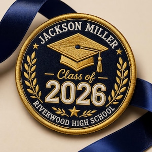 May include: Embroidered graduation patch with the text "Jackson Miller Class of 2026 Riverwood High School". The patch is navy blue with gold embroidery, a graduation cap, and laurel leaves. A navy blue ribbon is in the background.