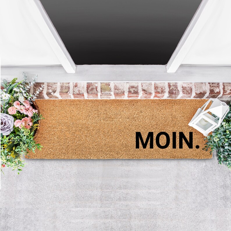 May include: A brown coir doormat with the word "MOIN." printed in black.