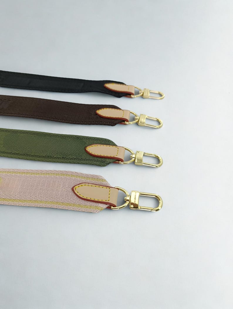 Puede incluir: Cuatro correas de bolso coloridas en negro, marr&oacute;n, verde oliva y rosa con herrajes dorados. Cada correa tiene un acento de cuero y un cierre dorado. Las correas se muestran sobre un fondo blanco.
