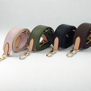 Puede incluir: Cuatro correas ajustables para bolsos en rosa, verde oliva, negro y marr&oacute;n. Cada correa presenta herrajes met&aacute;licos dorados, incluidos cierres y anillos, y detalles de cuero. Las correas est&aacute;n enrolladas, mostrando su textura y color.