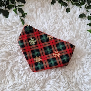 Könnte beinhalten: Hundebandana mit rotem, grünem und braunem Karomuster und goldenen Schneeflocken. Der Rand ist rot und der Stoff weich. Ein festliches Accessoire für die Weihnachtszeit.