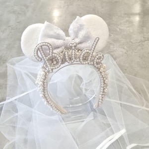 May include: White bridal headband with a pearl and silver embellishment that says "Bride" and a white tulle veil.
