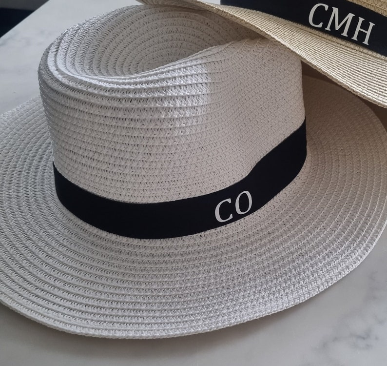 May include: White straw hat with a black band and white embroidered initials "CO".