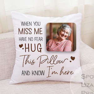 May include: White pillow with brown text that reads "When you miss me have no fear hug this pillow and know I'm here". A photo of a woman is in the top right corner of the pillow. The text "Spotted Lizard Prints" is in the bottom right corner.