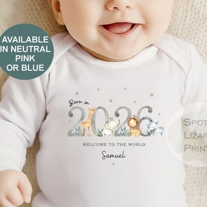 May include: White long-sleeved baby bodysuit with a grey print of the year 2026 with animals and the text "Born in" and "Welcome to the world Samuel". The bodysuit is available in neutral, pink, or blue.