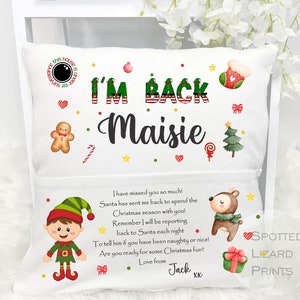 May include: A white pillow with a pocket on the back. The front of the pillow has the text "I'M BACK Maisie" in black with a green elf hat and a red stocking. The back of the pillow has a green elf, a reindeer, and the text "I have missed you so much! Santa has sent me back to spend the Christmas season with you! Remember I will be reporting back to Santa each night To tell him if you have been naughty or nice! Are you ready for some Christmas fun? Love from Jack xx".