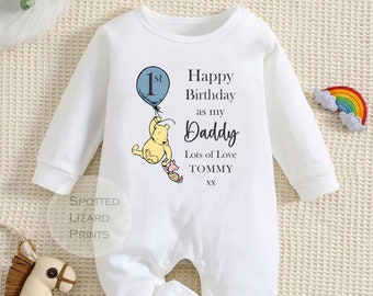 May include: White long-sleeve baby onesie with a Winnie the Pooh character holding a blue balloon that says "1st". The onesie has the text "Happy Birthday as my Daddy Lots of Love TOMMY xx"