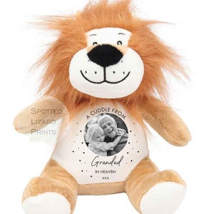 May include: A plush lion toy with tan fur, a white face, and a brown mane. The chest features a circular design with a black and white photograph of a child and an adult, the text A CUDDLE FROM, Grandad, IN HEAVEN, xxx, and small stars.