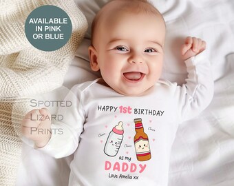 May include: A white baby onesie with the text "Happy 1st Birthday" and a cartoon illustration of a baby bottle and a beer bottle. The text "as my Daddy" is below the illustrations. The onesie is available in pink or blue.