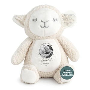 May include: A cream-colored plush lamb toy with a smooth white face and embroidered closed eyes. The belly features a circular black and white photograph of a child and an adult with the text A CUDDLE FROM GRANDAD IN HEAVEN xxx.