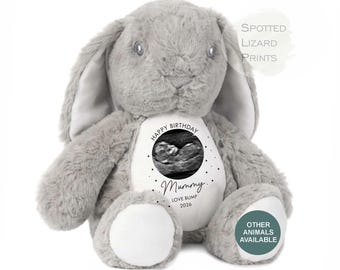May include: A grey plush rabbit with long ears and a white belly patch. The patch features a black and white ultrasound image, the text "HAPPY BIRTHDAY Mummy LOVE BUMP 2026", and small star icons. The text "SPOTTED LIZARD PRINTS" and "OTHER ANIMALS AVAILABLE" appear.