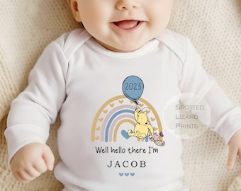 Könnte beinhalten: Ein weißer langärmeliger Baby-Strampler mit einem Regenbogen, einem gelben Bären, der einen blauen Ballon mit der Zahl 2025 hält, und dem Text "Well hello there I'm JACOB".