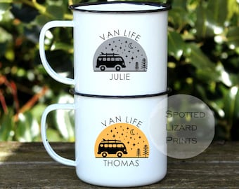 May include: Two white enamel mugs with black rims stacked vertically. The top mug features a gray semi-circle with a black van, stars, moon, trees, and the text "VAN LIFE JULIE". The bottom mug has an orange semi-circle with the same design and "VAN LIFE THOMAS".