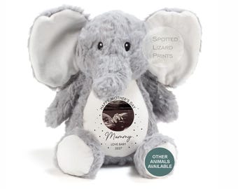 May include: A grey plush elephant toy with large ears and a white belly patch. The belly features a circular ultrasound image, the text "HAPPY MOTHER'S DAY", "Mummy", "LOVE BABY", and "2027". The toy has dark eyes and white foot pads.