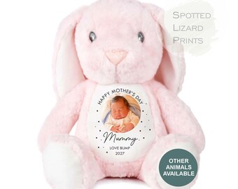 May include: A soft pink plush rabbit with long ears and a white belly patch featuring a circular photo of a baby. The text reads HAPPY MOTHER'S DAY, Mummy, LOVE BUMP, 2027. Additional text includes SPOTTED LIZARD PRINTS and OTHER ANIMALS AVAILABLE.