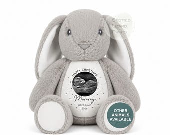 May include: A soft grey plush rabbit toy with long ears and white foot pads. The belly features a circular design with a black and white ultrasound image, the text "HAPPY CHRISTMAS Mummy LOVE BUMP 2026," and a dotted border. A watermark reads "SPOTTED LIZARD PRINTS."