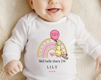 Könnte beinhalten: Ein weißer Langarm-Strampler mit einem rosa und goldenen Regenbogen, einer Winnie Puuh-Figur, die einen rosa Ballon mit der Zahl 2025 hält, und dem Text "Well hello there I'm LILY".