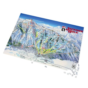 May include: A colorful Jackson Hole ski resort map puzzle. The puzzle features a detailed illustration of the ski slopes, trails, and surrounding landscape. The puzzle includes the Jackson Hole logo and the U.S. Forest Service logo.