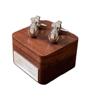 May include: Silver golf bag cufflinks displayed on a dark wooden box with a silver nameplate. The nameplate reads "No 1: Daddy Love from Nathan". The cufflinks feature golf club designs.