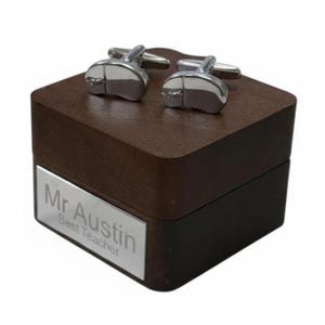 Può includere: Un paio di gemelli argentati a forma di mouse per computer poggia su una scatola di legno marrone scuro. La scatola ha una targhetta argentata con la scritta "Mr Austin Best Teacher".