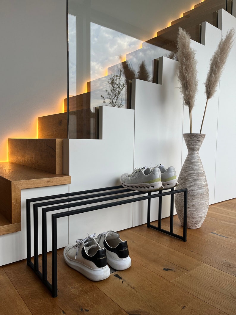 Schuhregal aus Metall in schwarz im Eingangsbereich mit einer Treppe im Hintergrund