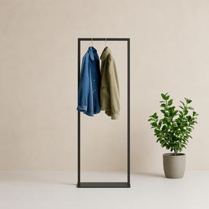 Pode incluir: Um cabide de metal preto com duas camisas penduradas. As camisas são azul claro e verde escuro. O cabide está em um chão bege claro.