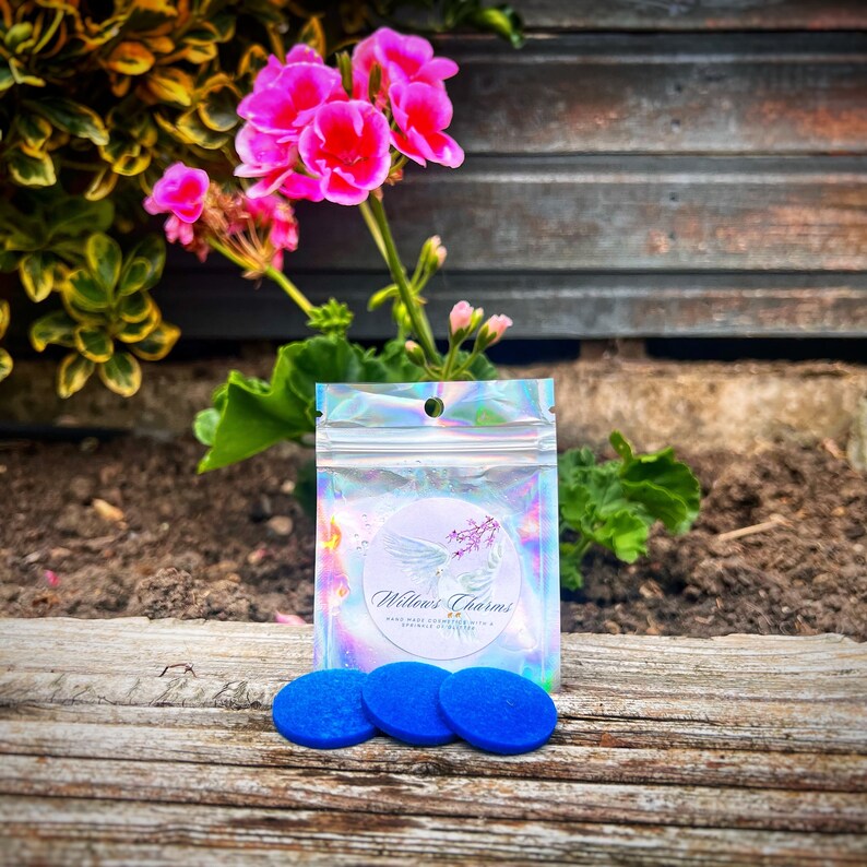 May include: Three blue round wax melts in a clear plastic bag with a white label that says "Willow's Charms" and "Hand-poured soy candles with a natural essential oil blend."