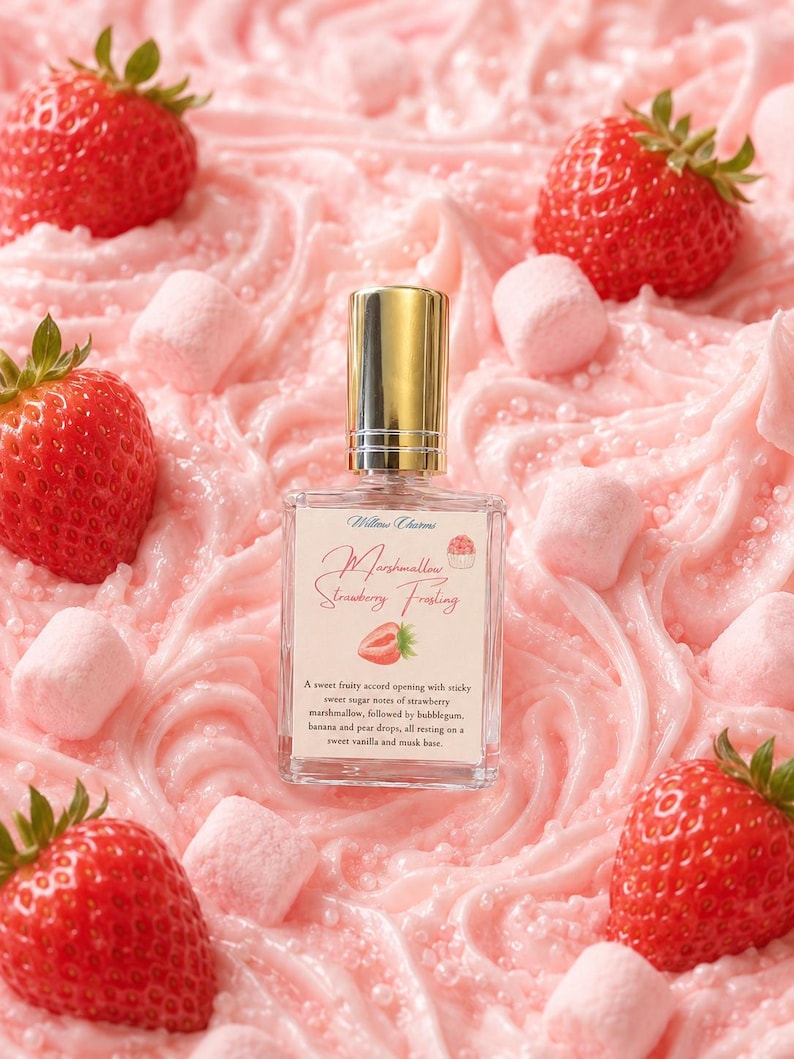 K&ouml;nnte beinhalten: Ein rechteckiger Glasparf&uuml;mflakon mit goldenem Verschluss und einem Etikett mit der Aufschrift Willow Charms Marshmallow Strawberry Frosting, umgeben von frischen roten Erdbeeren und kleinen rosa Marshmallows auf rosa Zuckerguss.