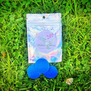 May include: Three blue felt circles in a small clear plastic bag with a white label that says "Willow's Charms Hand Made Cosmetics with a Sprinkle of Glitter".