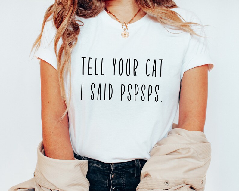 Puede incluir: Camiseta blanca con texto negro que dice "Dile a tu gato que dije pspsps."