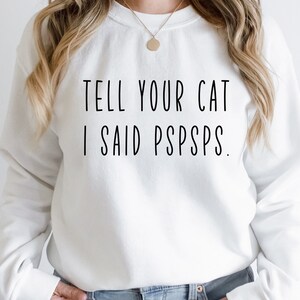 Puede incluir: Sudadera blanca con el texto "TELL YOUR CAT I SAID PSPSPS."