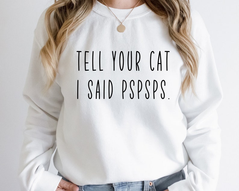 Puede incluir: Sudadera blanca con el texto "TELL YOUR CAT I SAID PSPSPS."
