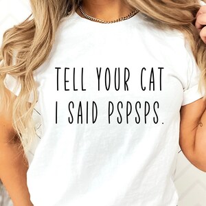Puede incluir: Camiseta blanca con el texto "TELL YOUR CAT I SAID PSPSPS."