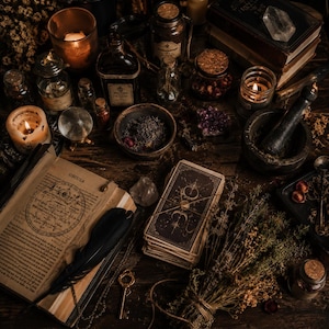 May include: A still-life arrangement of mystical items on a dark wooden surface. The scene includes lit candles, open books, tarot cards, glass bottles, a crystal ball, dried herbs, and a mortar and pestle. The overall color palette is warm, with shades of brown and gold.