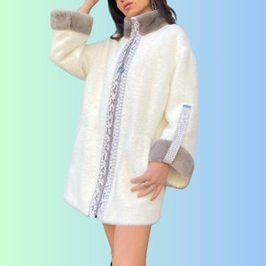 Pode incluir: Casaco de pele sintética branca com fecho de correr e guarnição de pele castanha no colarinho e punhos. O casaco tem um detalhe de fecho de correr decorativo na frente.