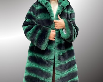 May include: A long, green and black striped faux fur coat with a hood. The coat has a zip fastening and is made of soft, plush fabric.