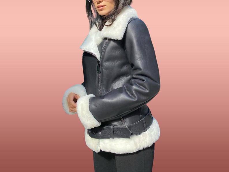 以下が含まれることがあります： 白いフェイクファーの襟とトリムが付いた黒い革のジャケット。ジャケットはジッパー留めとウエストにベルトが付いています。