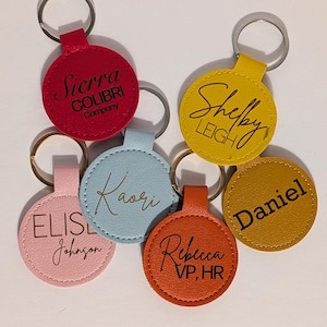 Puede incluir: Una colecci&oacute;n de coloridos llaveros con anillos plateados. Cada llavero es de un color diferente, incluyendo rojo, amarillo, naranja, rosa y azul. Los llaveros tienen nombres y nombres de empresas.