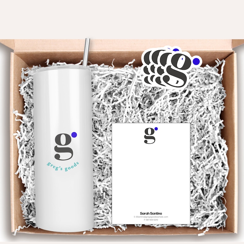 Peut inclure: Une bo&icirc;te cadeau remplie de papier blanc d&eacute;chiquet&eacute; contenant un gobelet blanc avec un logo bleu et noir qui dit "Greg's Goods", un bloc-notes blanc avec un logo bleu et noir qui dit "g", et trois autocollants avec le m&ecirc;me logo.