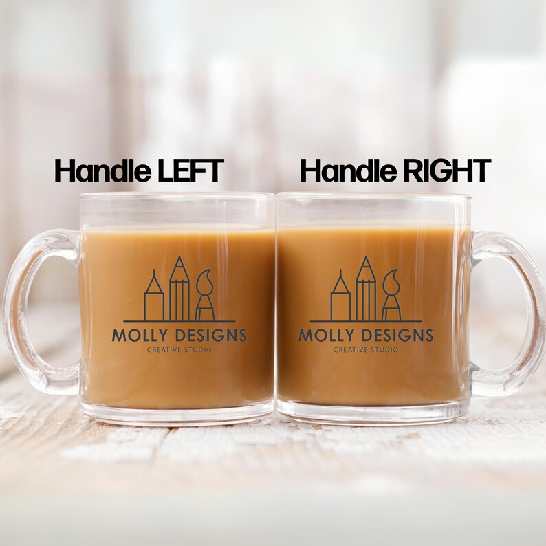 May include: Two clear glass mugs with handles on opposite sides. Both mugs contain a brown liquid and feature a black and white logo that says "Molly Designs Creative Studio" with a graphic of pencils and a paintbrush.
