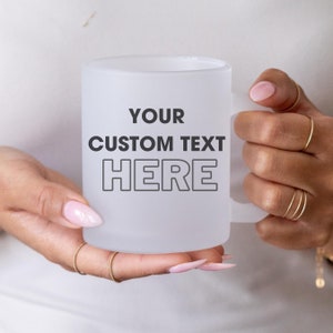 May include: White frosted mug with a black outline of the text "YOUR CUSTOM TEXT HERE" on the front.