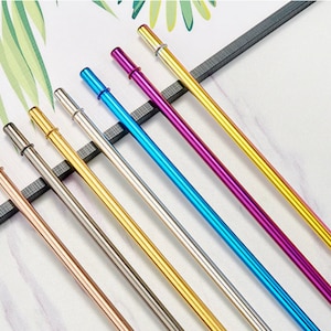 Op de afbeelding: Set van acht herbruikbare metalen drinkrietjes in verschillende kleuren, waaronder ros&eacute; goud, zilver, goud, grijs, blauw, paars en geel. De rietjes zijn allemaal even lang en hebben een afgeronde punt.
