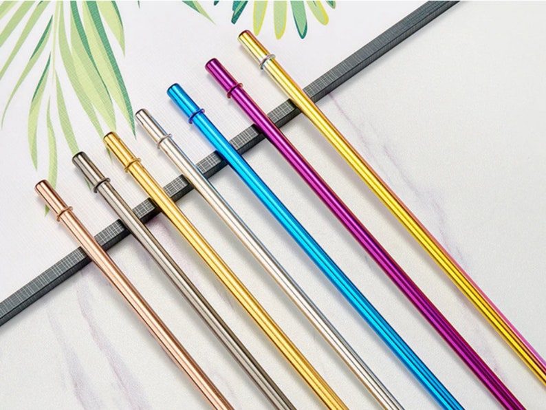 Op de afbeelding: Set van acht herbruikbare metalen drinkrietjes in verschillende kleuren, waaronder ros&eacute; goud, zilver, goud, grijs, blauw, paars en geel. De rietjes zijn allemaal even lang en hebben een afgeronde punt.