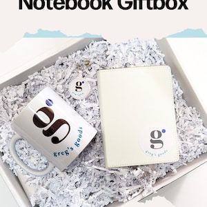 May include: A white gift box filled with white shredded paper. The box contains a white mug with a blue and black logo that says "g. greg's goods", a white notebook with a blue and black logo that says "g. greg's goods", and a white keychain with a blue and black logo that says "g. greg's goods". The box is labeled "CreatedSpark".