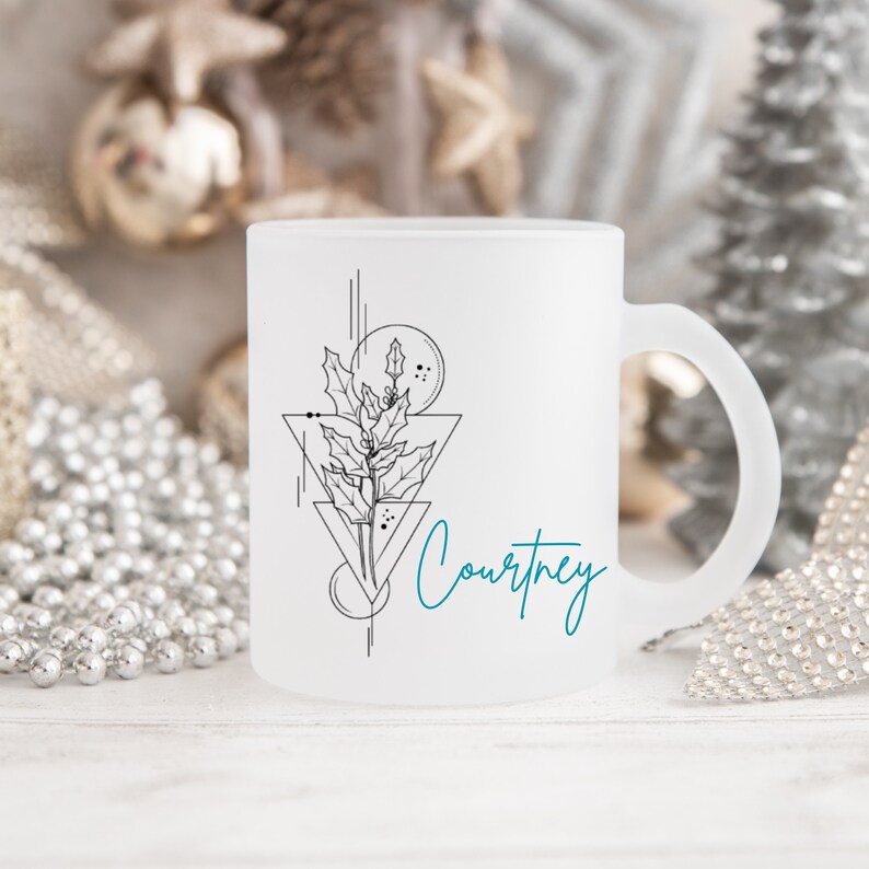 May include: White frosted mug with a black and white geometric design featuring a holly sprig and the name "Courtney" in teal blue lettering.